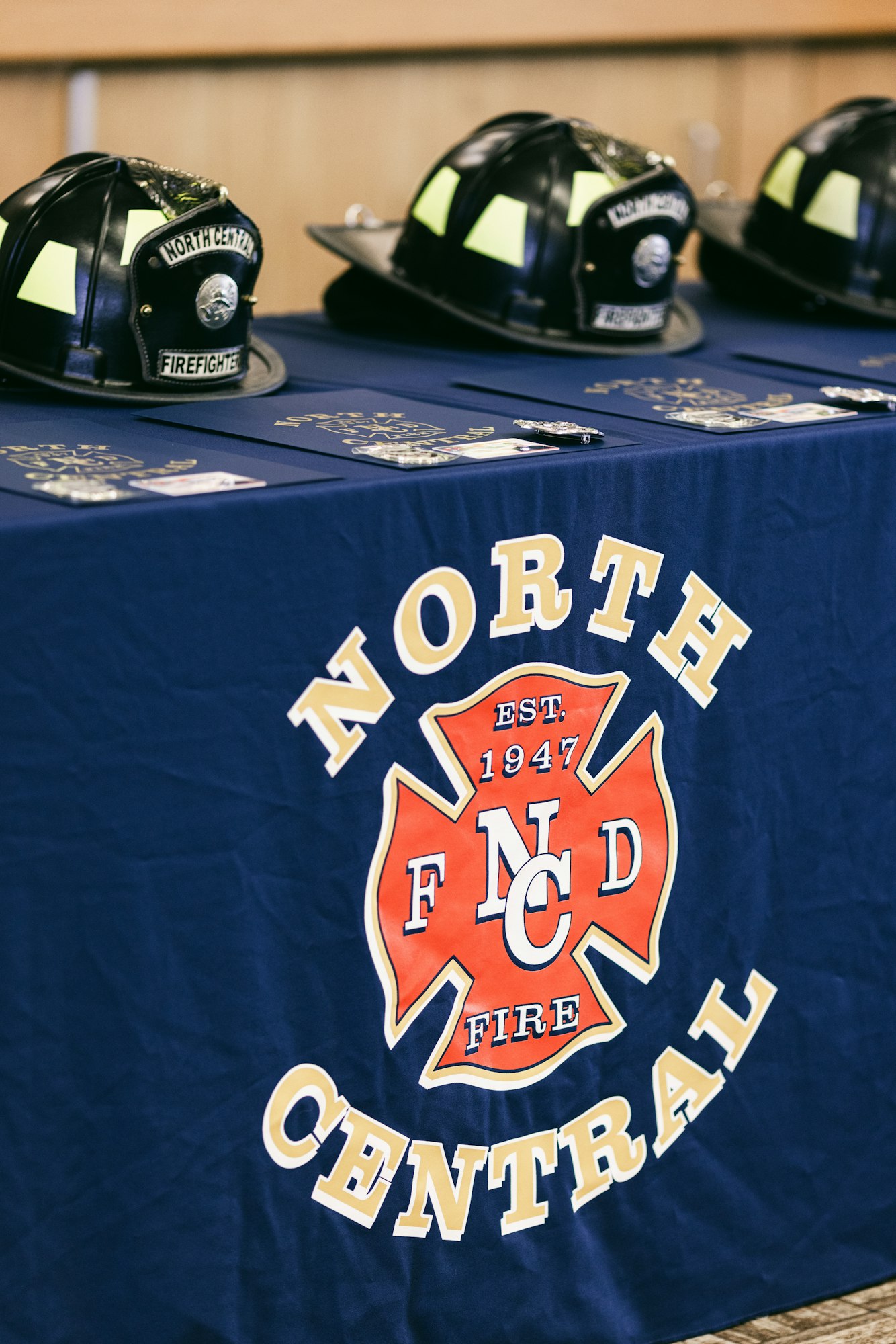 Firefighter helmets on a table with a "North Central Fire" logo cloth.