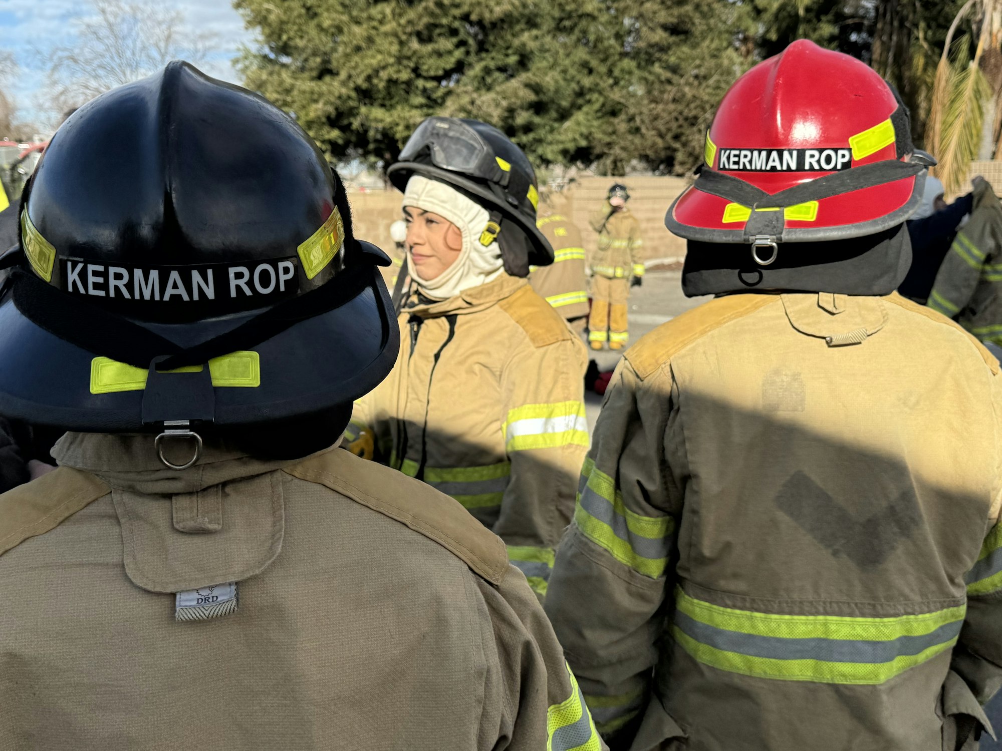 Firefighters in protective gear labeled "KERMAN ROP," standing outdoors.
