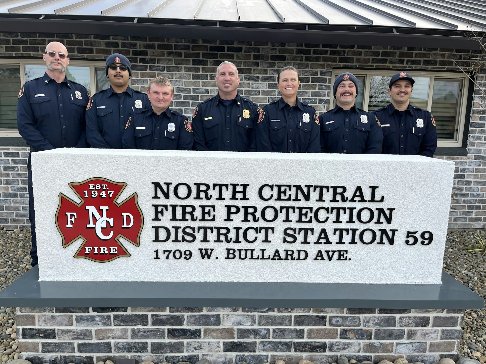 A group of firefighters stands in front of North Central Fire Protection District Station 59.