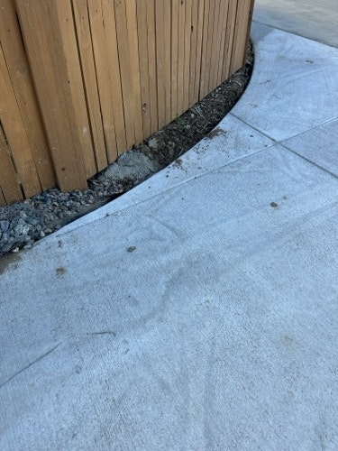 Concrete sidewalk beside a wooden fence with a gravel border.