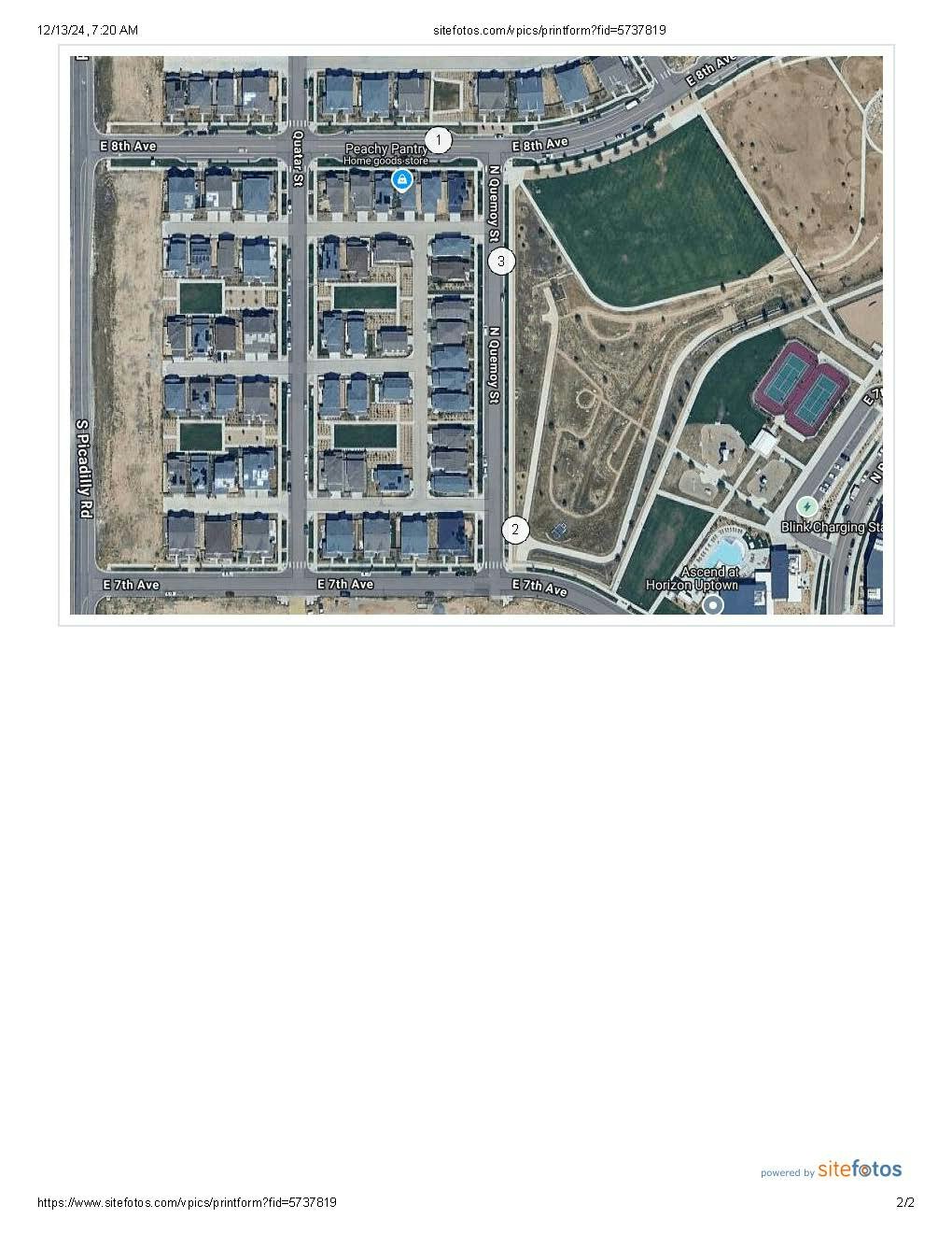 Aerial view of a residential area with houses, roads, a park, sports fields, and a charging station.