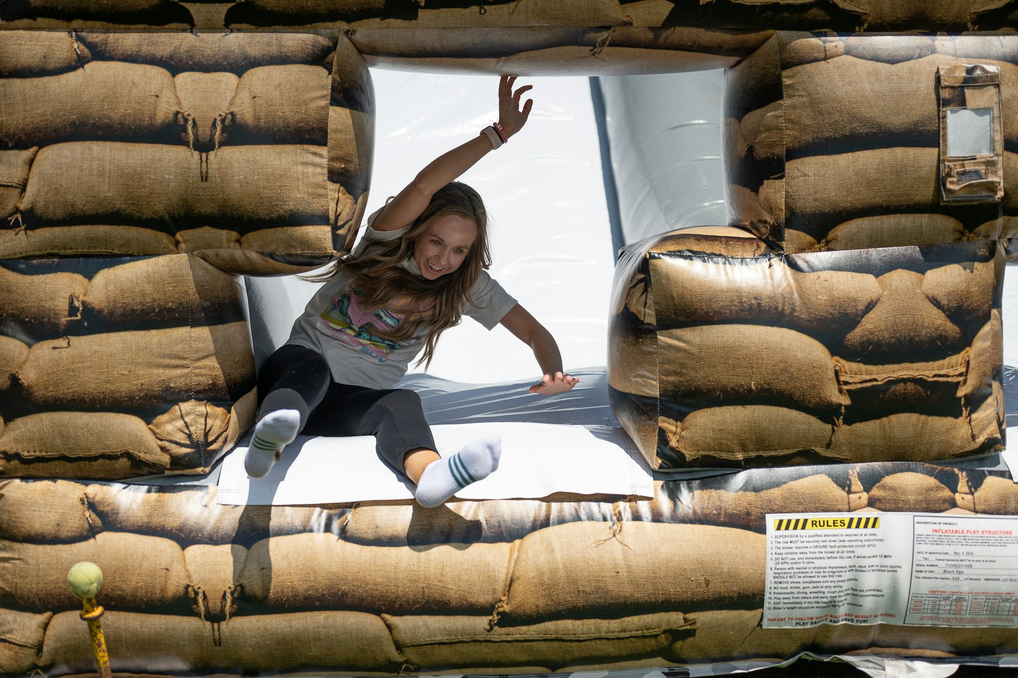 A person slides down an inflatable play structure designed to look like sandbags.