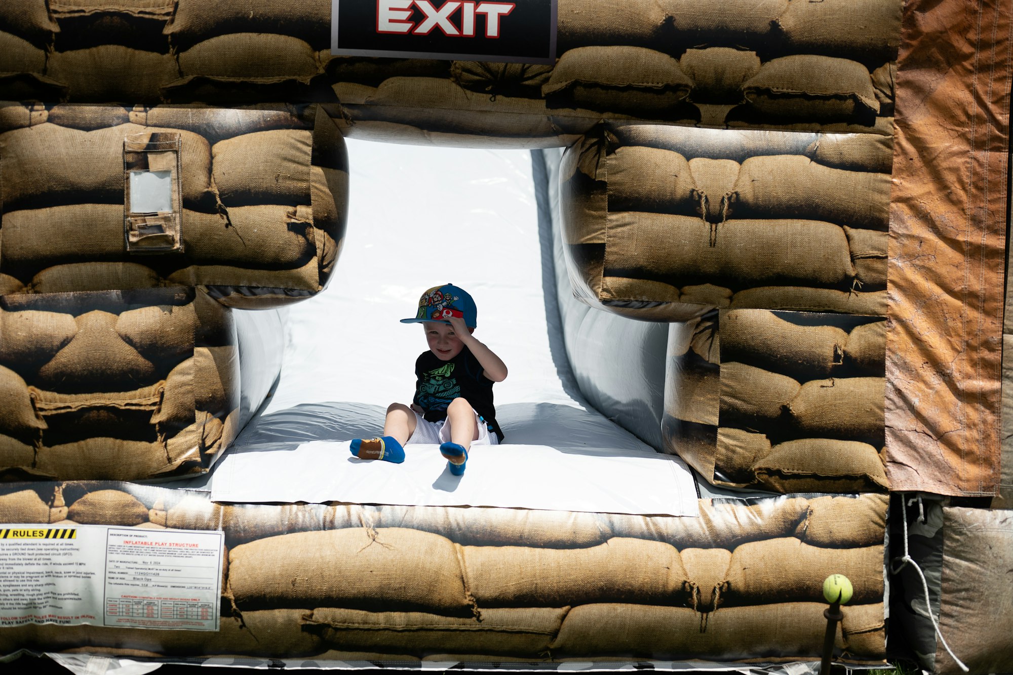 A child sliding out of an inflatable play structure with an "EXIT" sign above.
