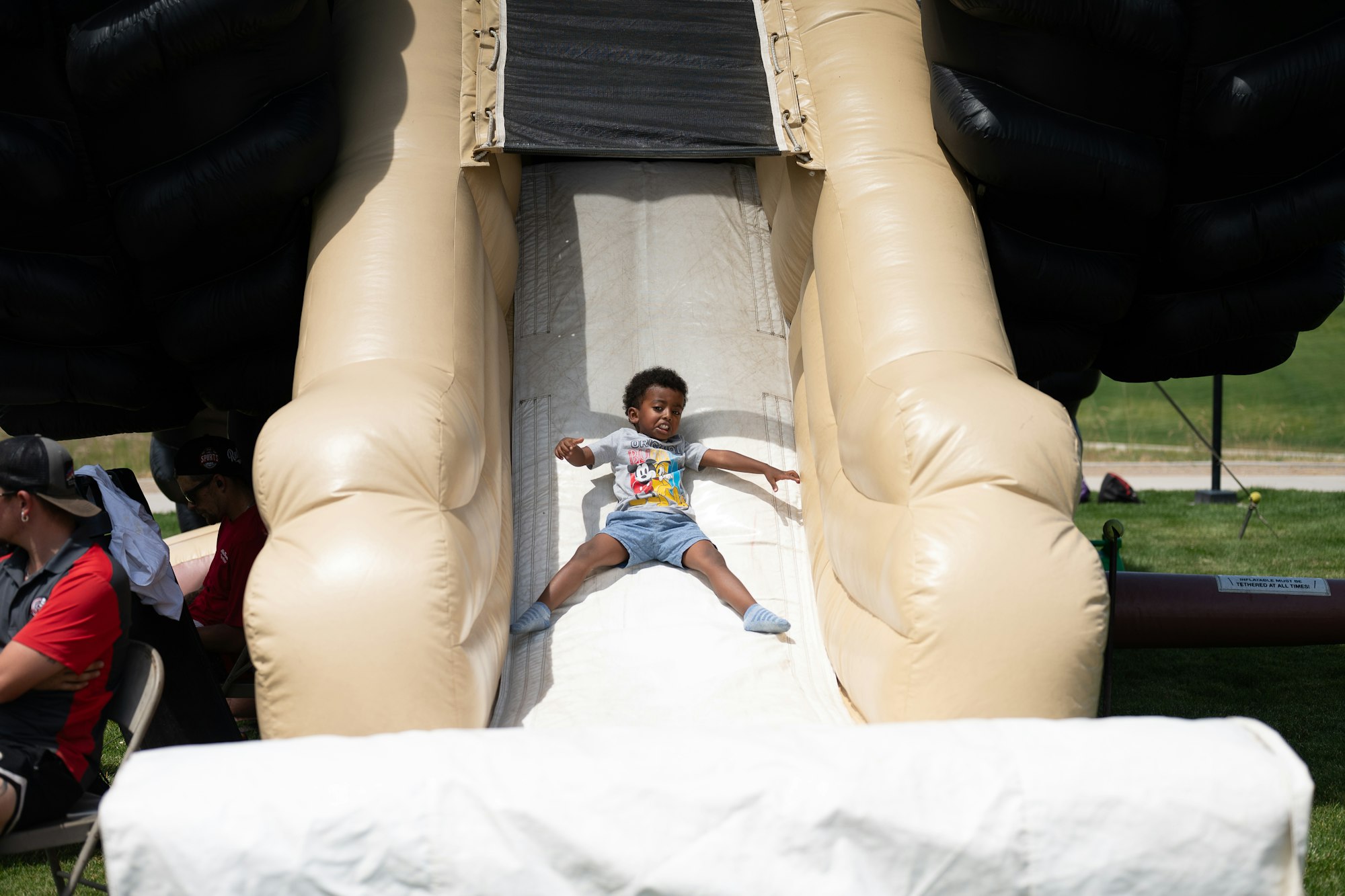 A child sliding down an inflatable slide at an outdoor event.
