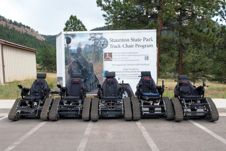 The image features several all-terrain track chairs lined up beside a sign for the Staunton State Park Track-Chair Program.