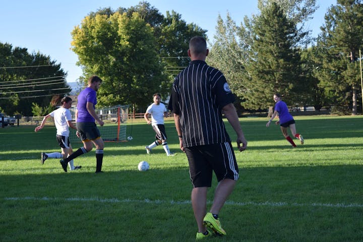 Adults playing soccer outside