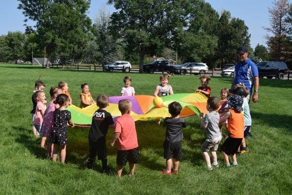 children holding a rainbow tarp