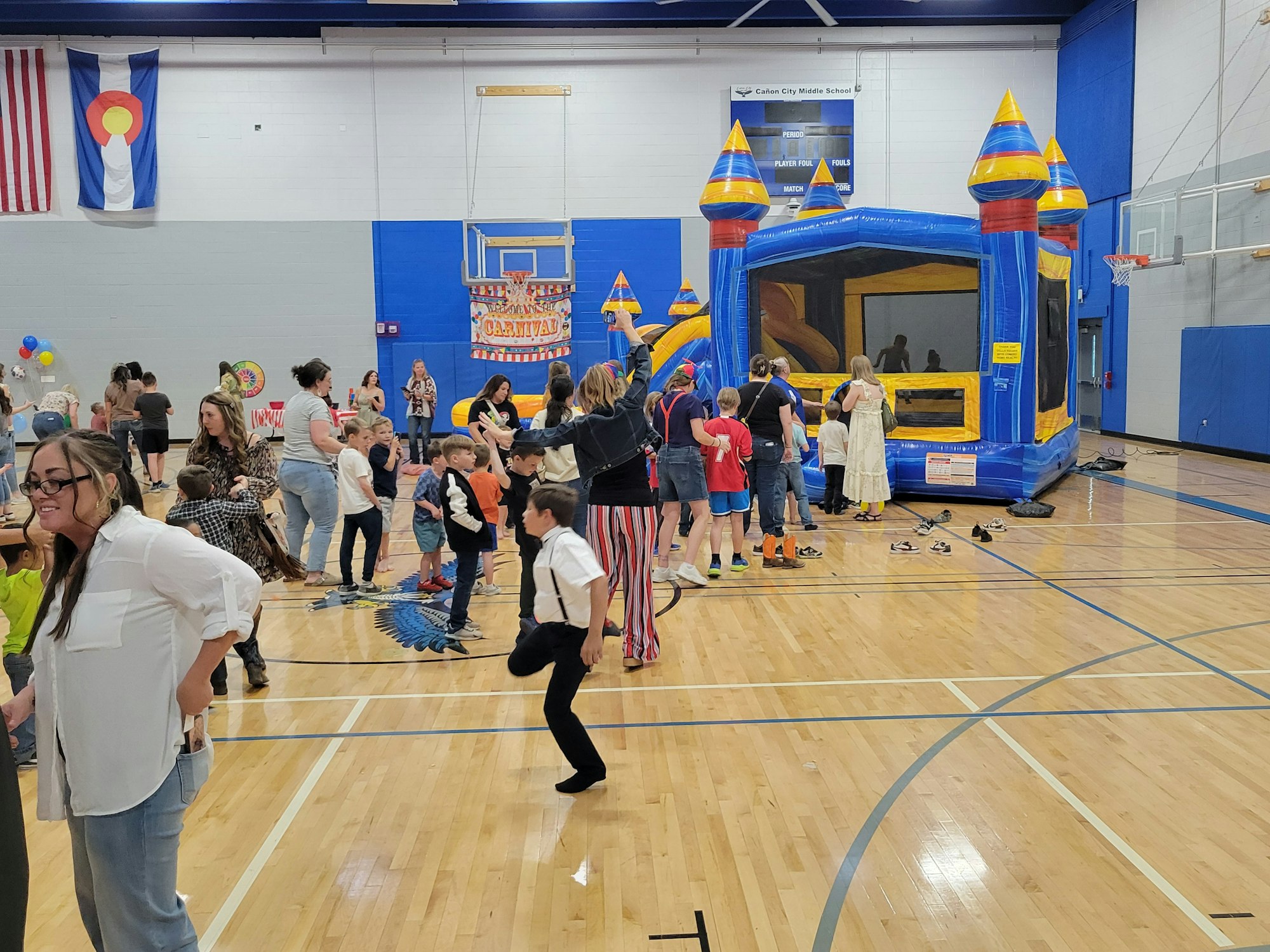 A lively indoor event with children and adults enjoying games, a bounce house, and festive decorations.