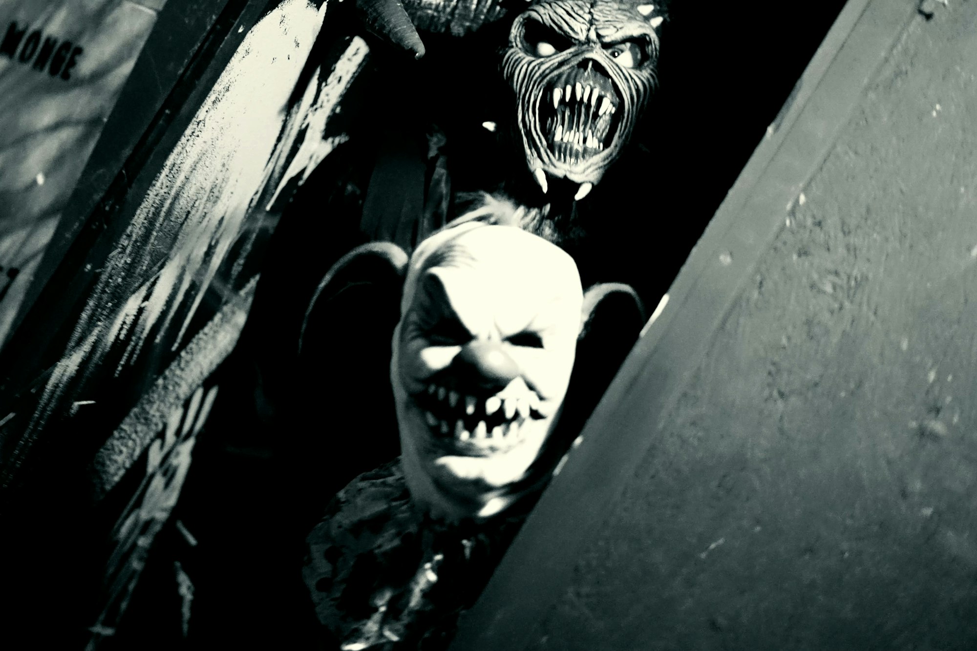 Two scary masks, one with large teeth and another clown-like, in a dark, eerie setting.