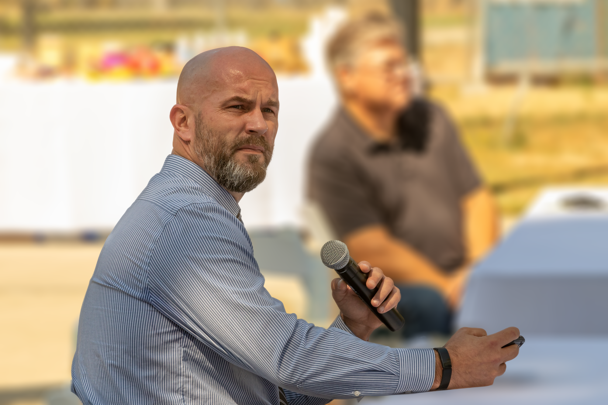 May contain: person, human, microphone, electrical device, crowd, and sitting