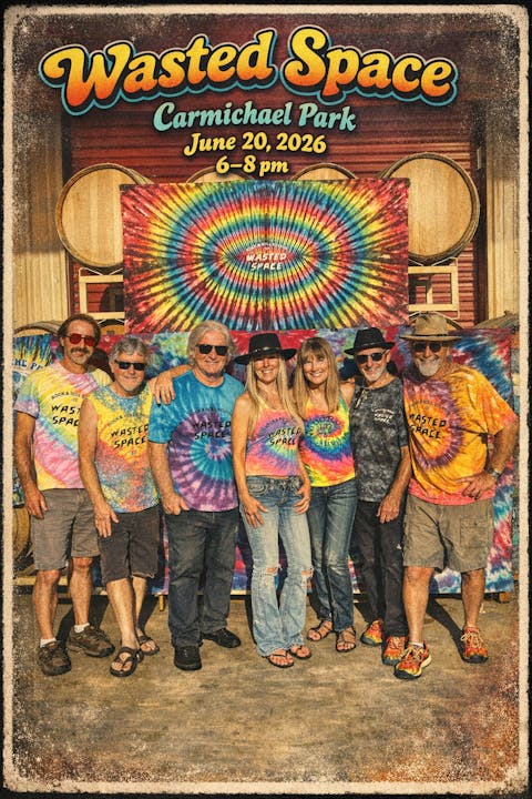 A group of people wearing tie-dye shirts posing in front of a colorful backdrop for the "Wasted Space" event at Carmichael Park.