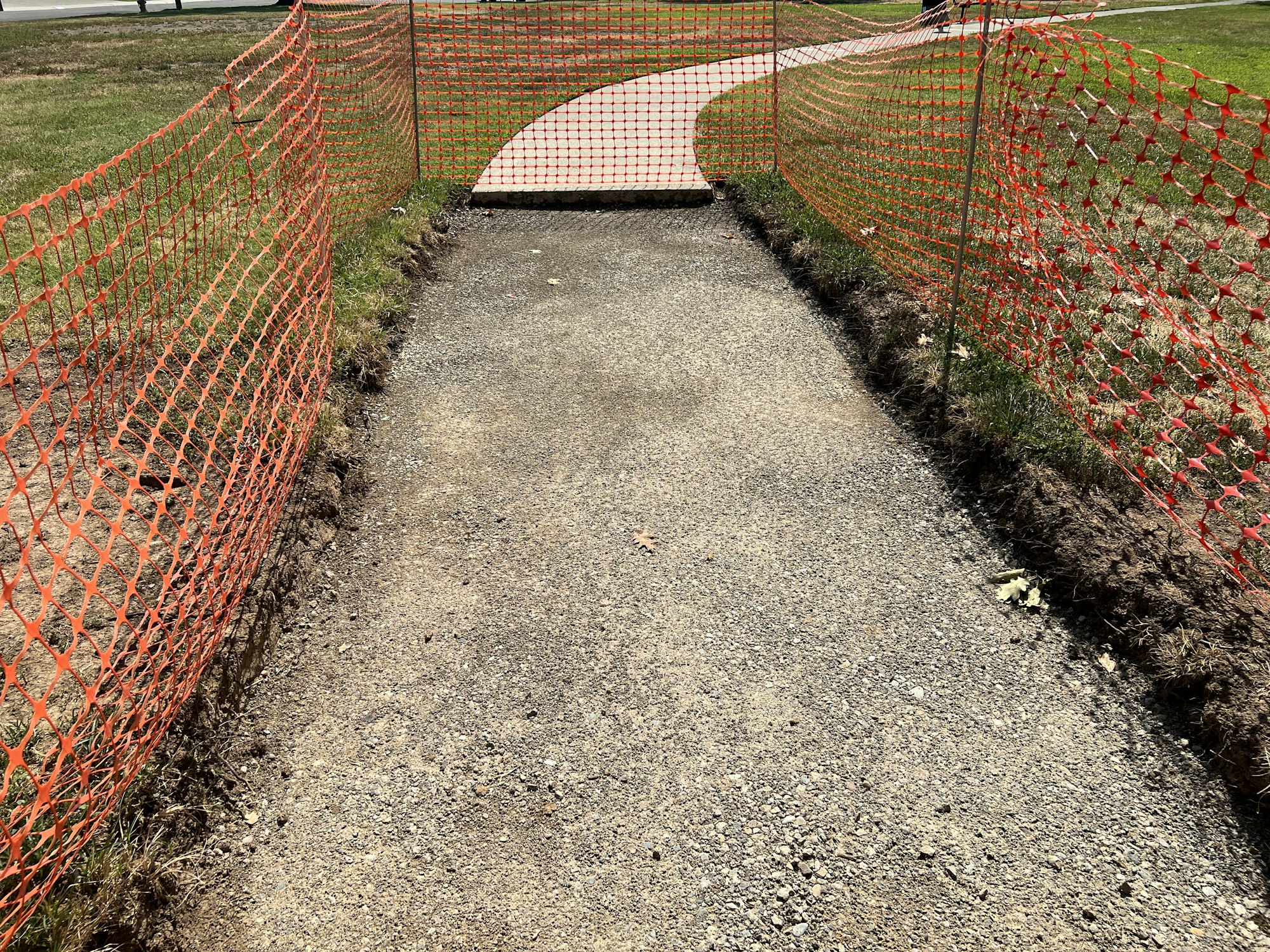 Pathway under construction with orange safety fencing on both sides.