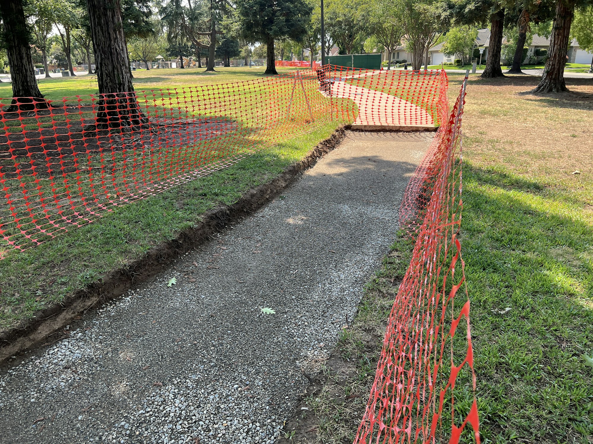 Pathway under construction in a park, marked by bright orange netting.