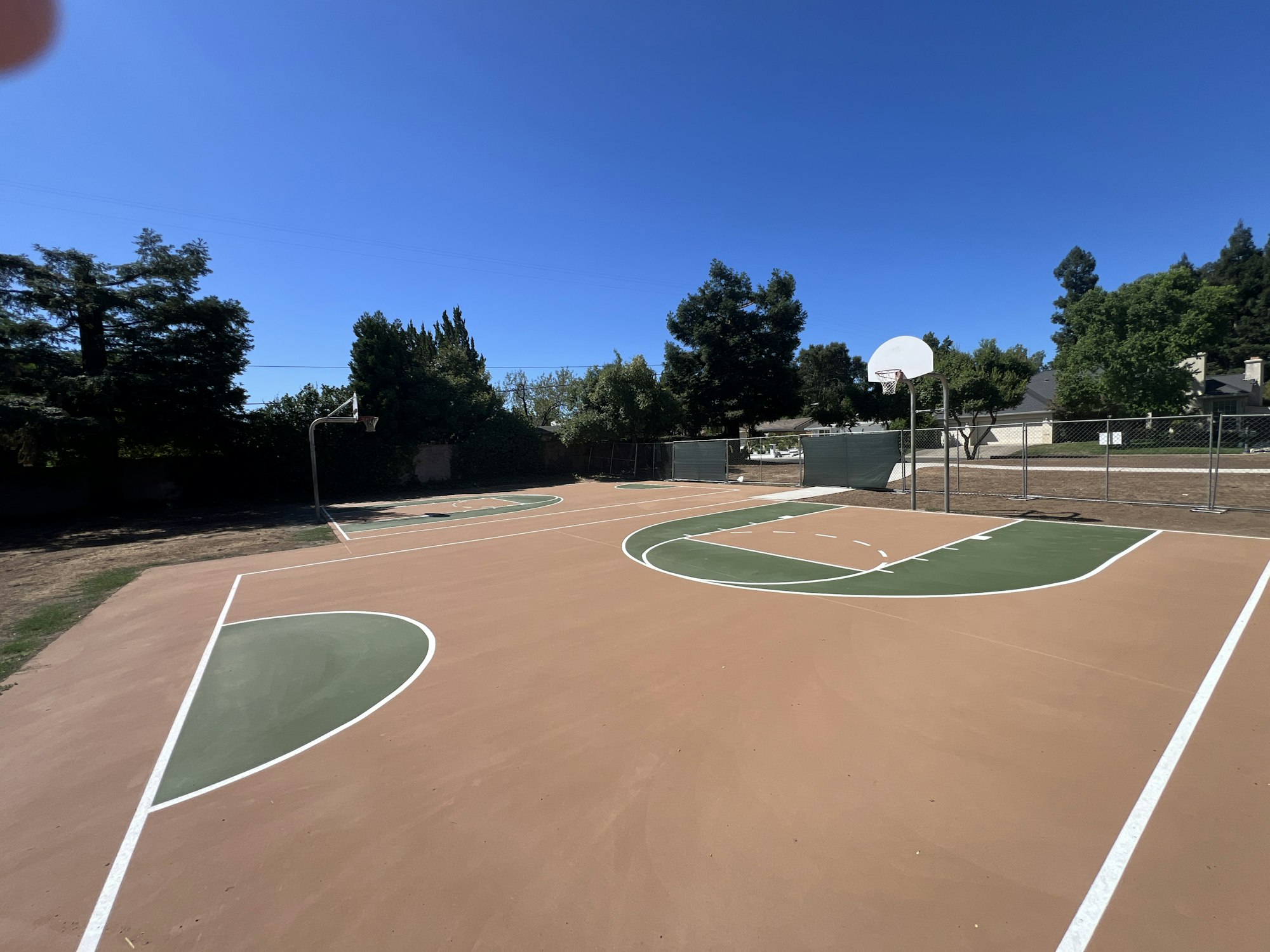 Outdoor basketball court with two hoops and clear sky.