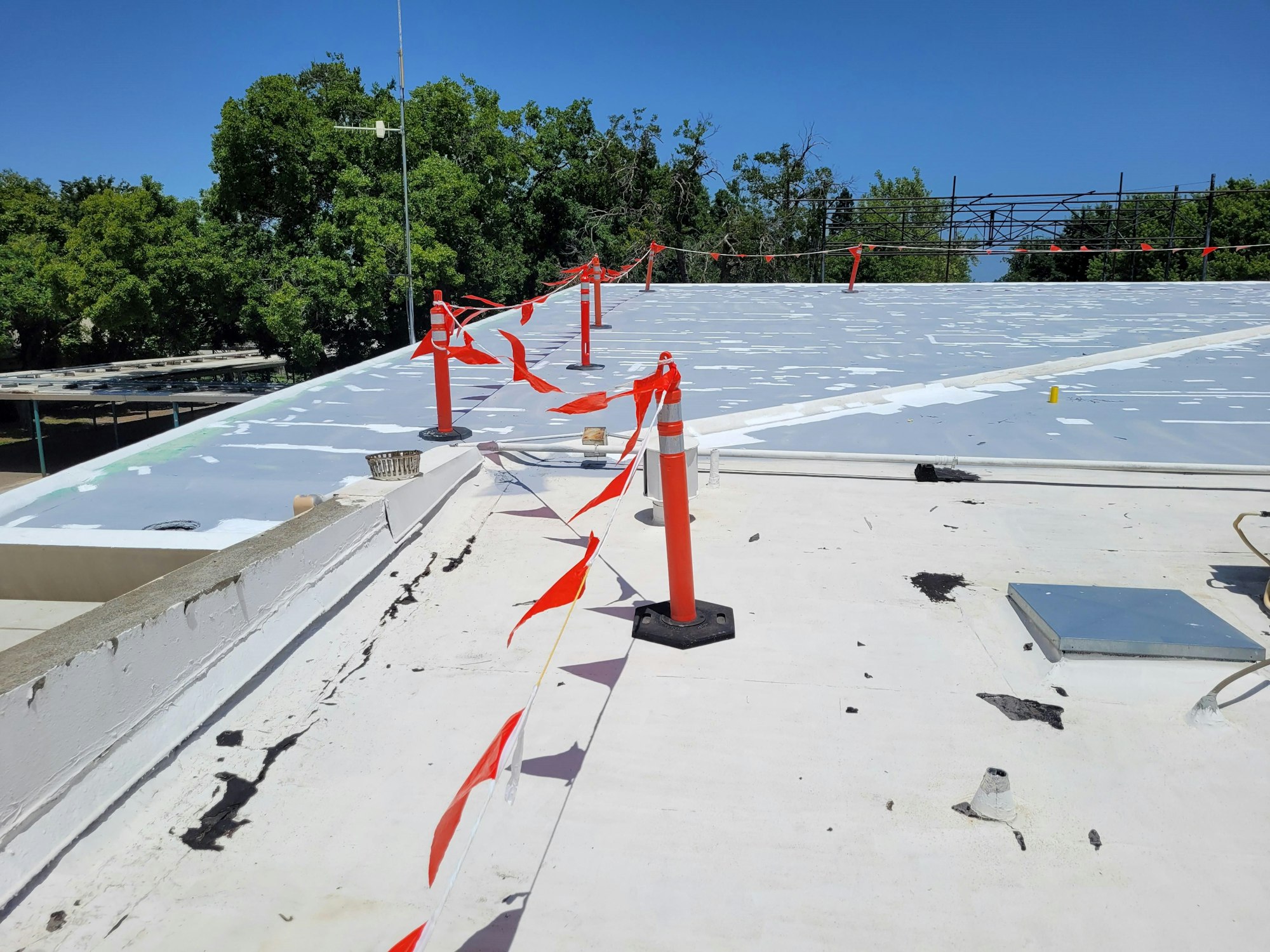 A rooftop with warning cones and red-and-white barrier tape indicating a hazard or construction zone.