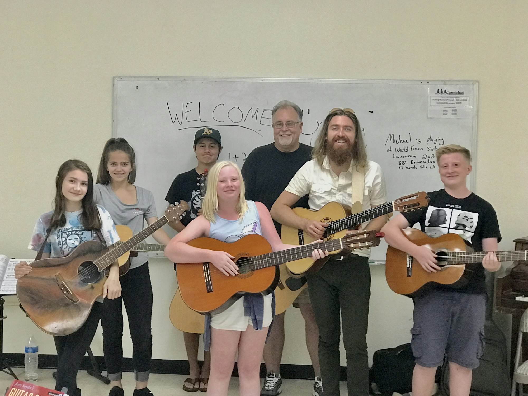 Guitar class: Six students and one instructor all holding their guitars.