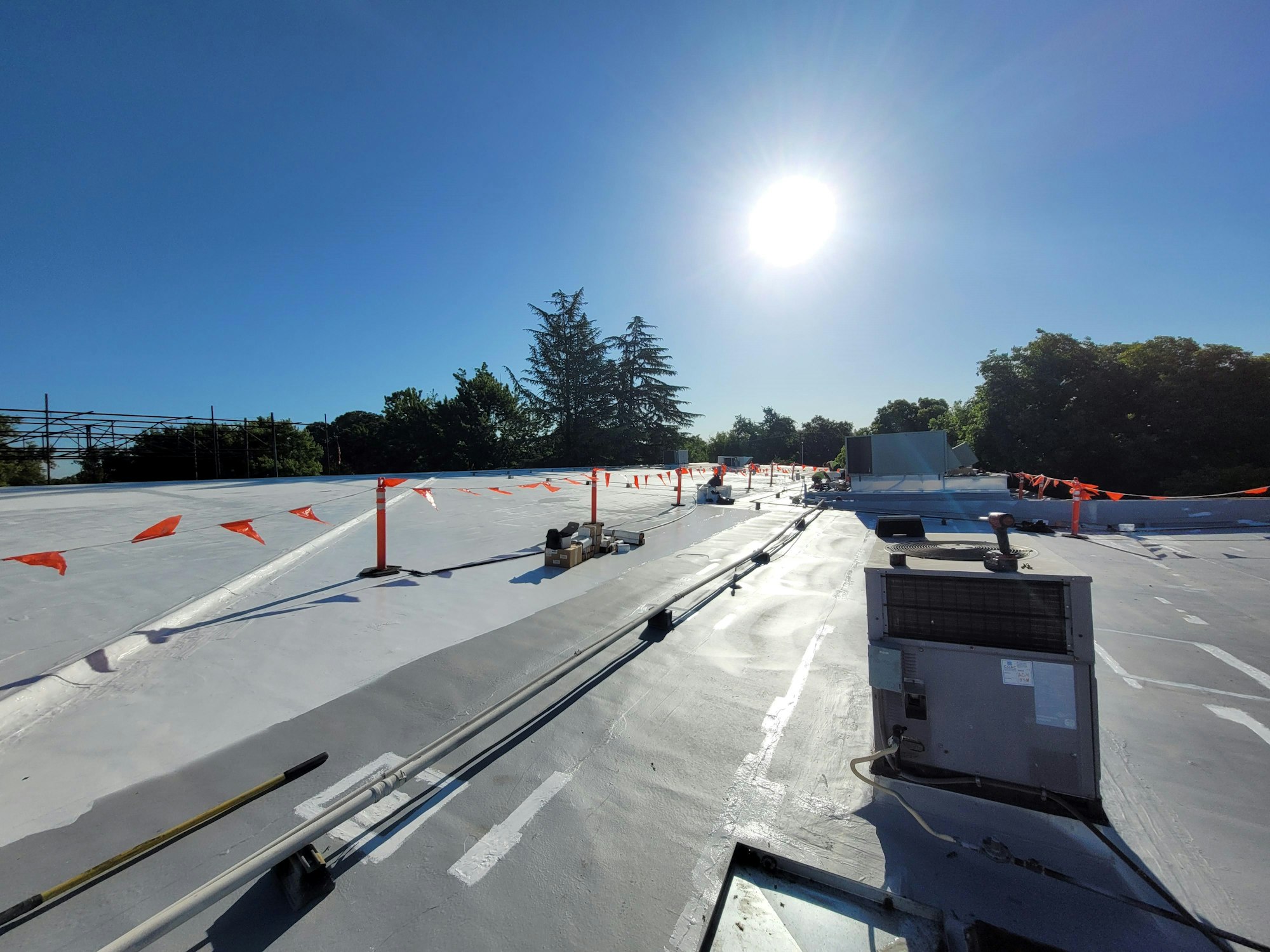 A flat roof with equipment and safety markers under a clear sky.