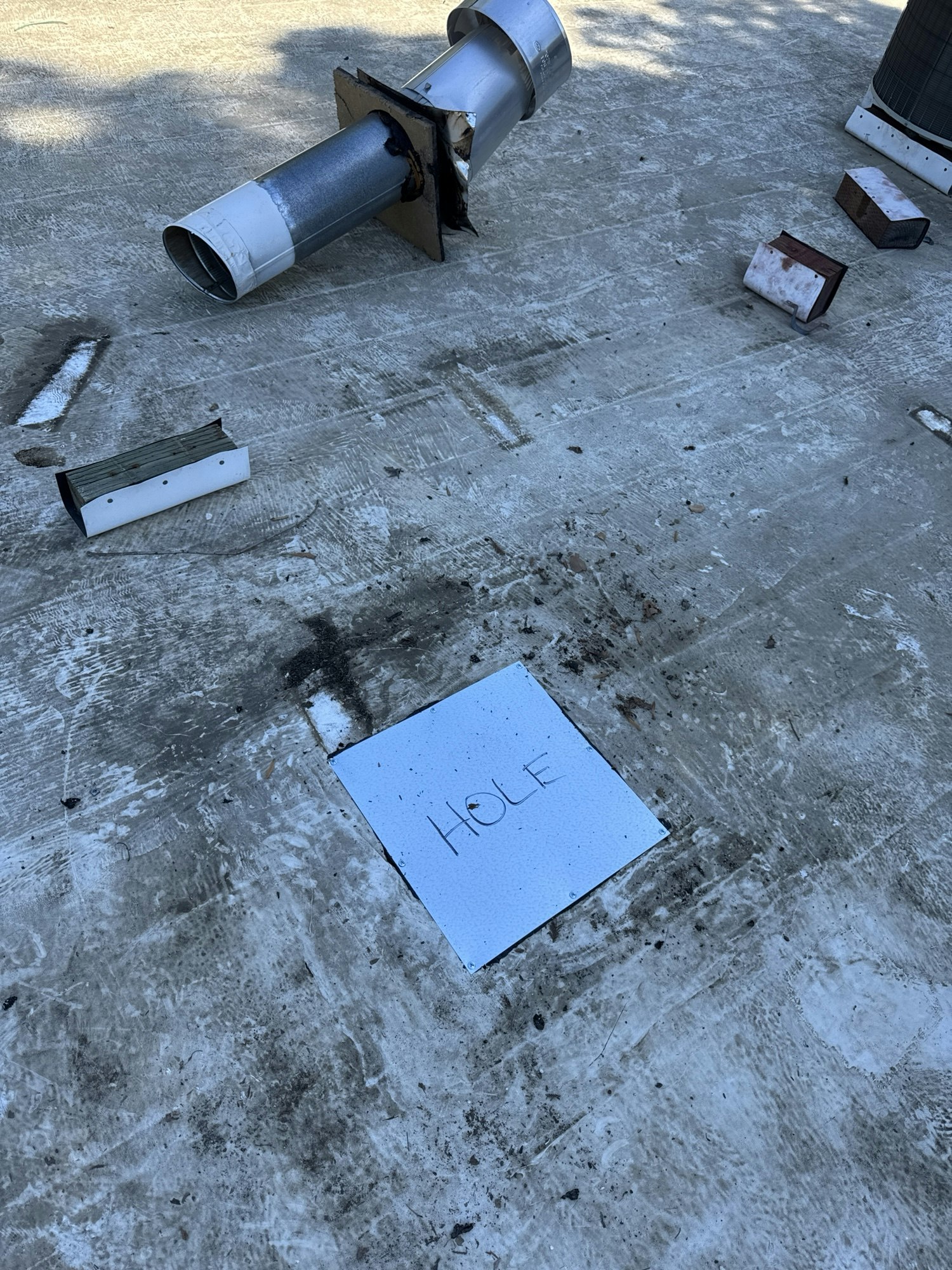 Debris and pipes on a concrete surface. A square tile labeled "HOLE."