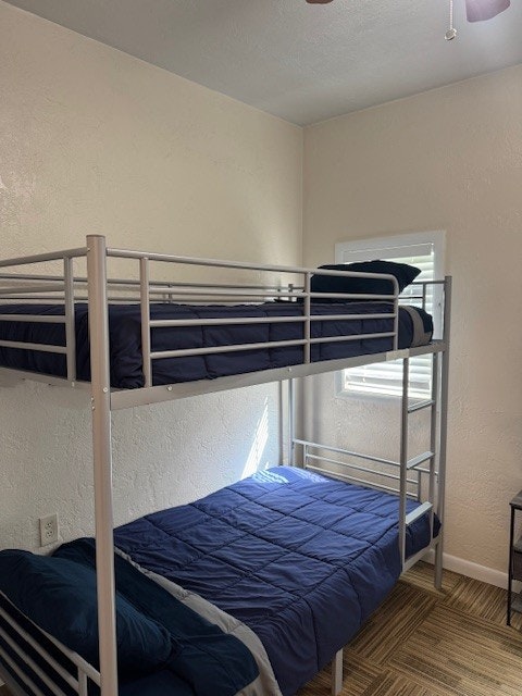 A small room with a metal bunk bed, blue bedding, and a window with blinds.