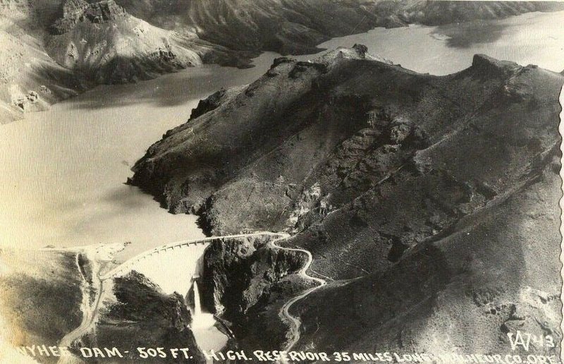 Aerial view of the Wyhe Dam, 505 ft high, with a reservoir 35 miles long, showcasing rugged terrain and water bodies.