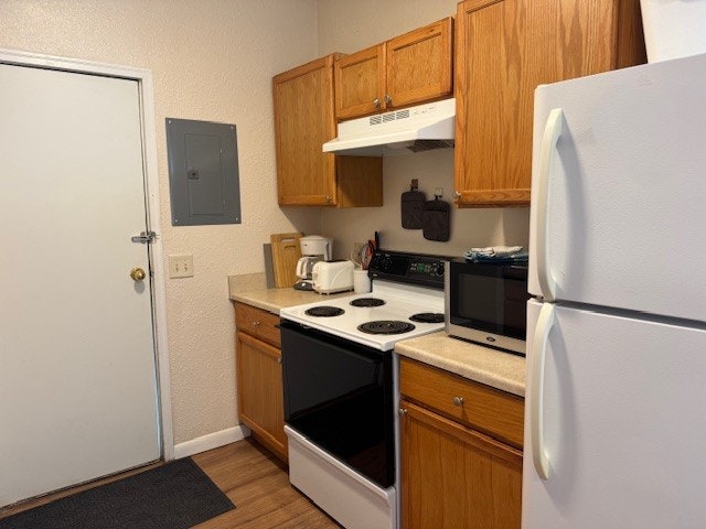 A kitchen with a white fridge, wooden cabinets, stove, microwave, toaster, cutting boards, and a range hood.