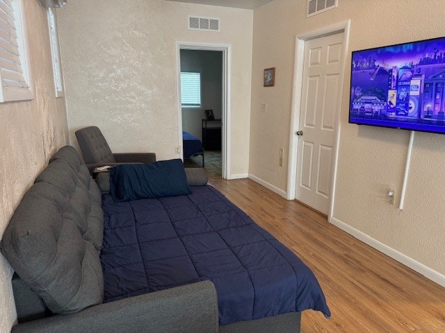 A small room with a sofa bed, TV on the wall, and another room visible through a doorway.