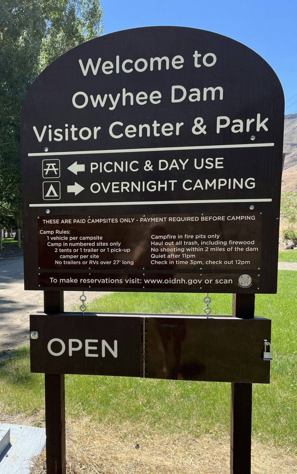 Sign for Owyhee Dam Visitor Center & Park, detailing camping rules, contact info, and status as "OPEN".