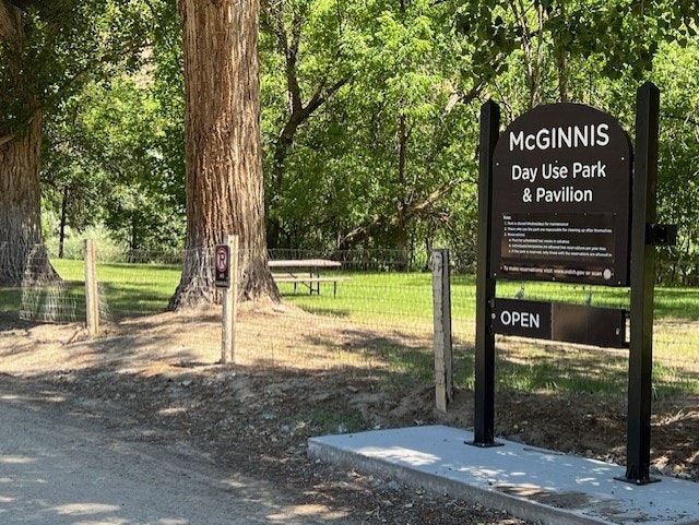 Sign for McGinnis Day Use Park & Pavilion, surrounded by trees, with a "No Parking" sign and the area is marked open.