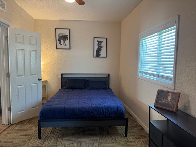 A bedroom with a bed, nightstand, lamp, framed art, dresser, and window blinds.