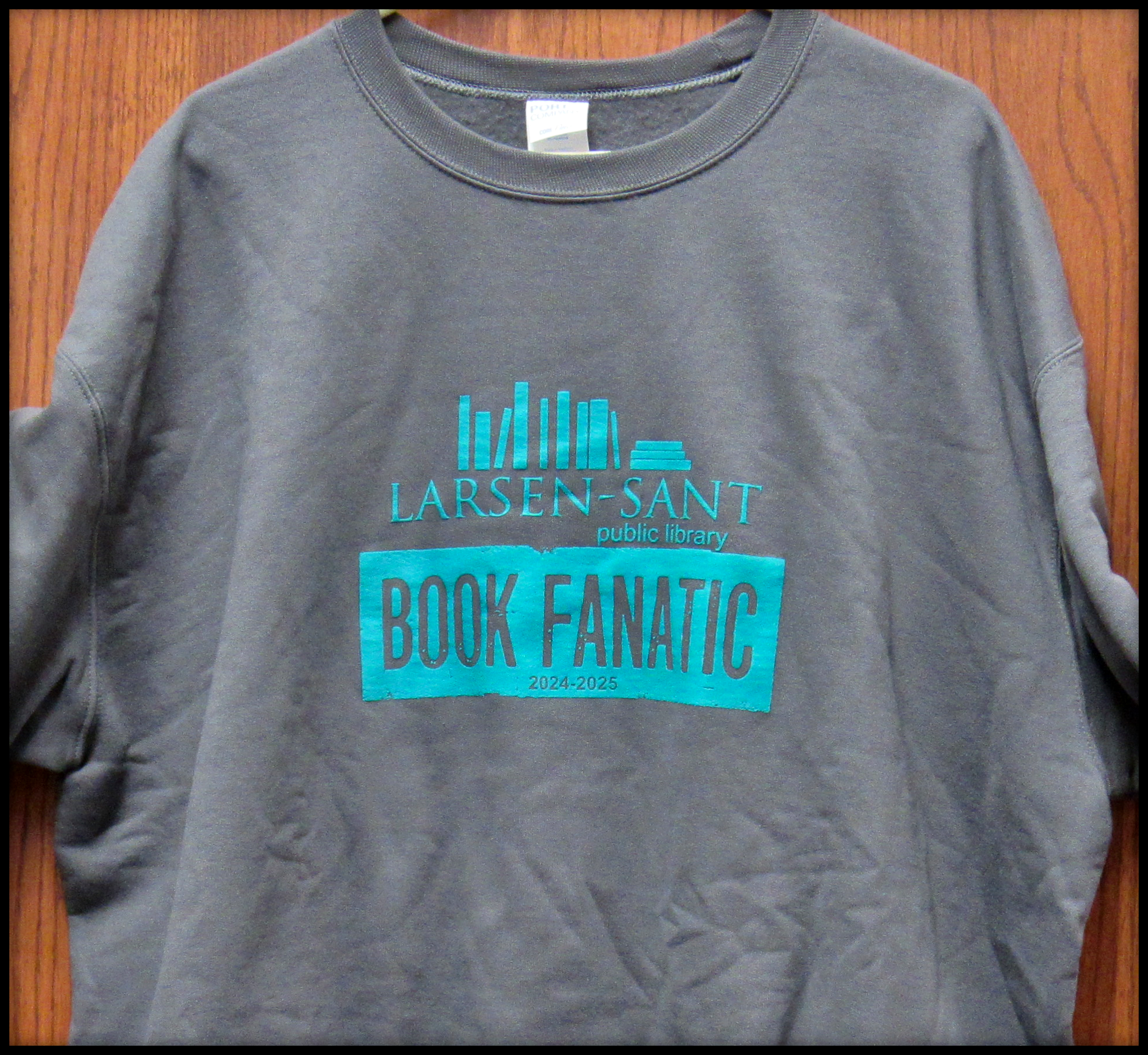 A gray sweatshirt with a "Larsen-Sant Public Library Book Fanatic" print for 2024-2025.