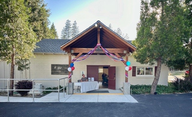 A building entrance decorated with balloons and streamers, with a person at a welcome table.