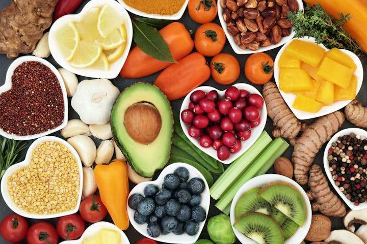 Assorted healthy foods including fruits, vegetables, nuts, and spices arranged neatly.