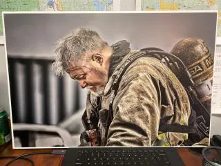 A photo of a weary firefighter in protective gear, looking down, with signs of exhaustion and dirt on his uniform.
