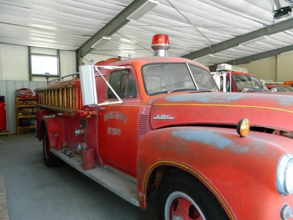 An antique red fire truck with a ladder on the side, parked indoors, showcasing vintage engineering and design.