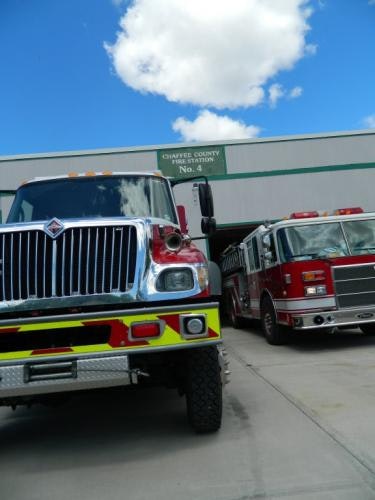 The image shows two fire trucks parked at Chaves County Fire Station No. 4 under a blue sky with clouds.