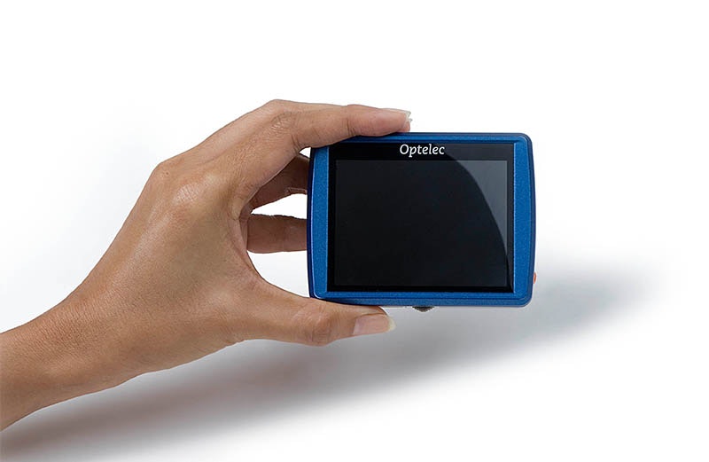 A hand holding a blue electronic device with a black screen, labeled "Optelec."