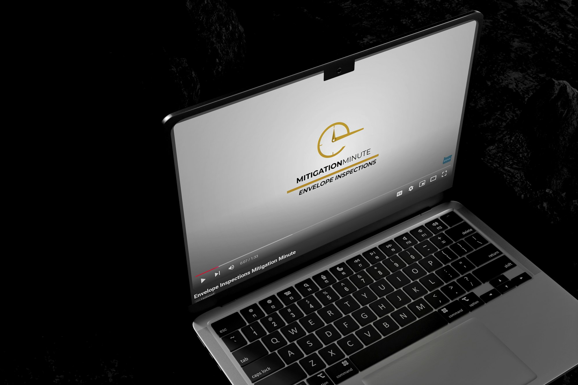 A laptop displaying a video titled "MITIGATIONMINUTE ENVELOPE INSPECTIONS" on a dark background.