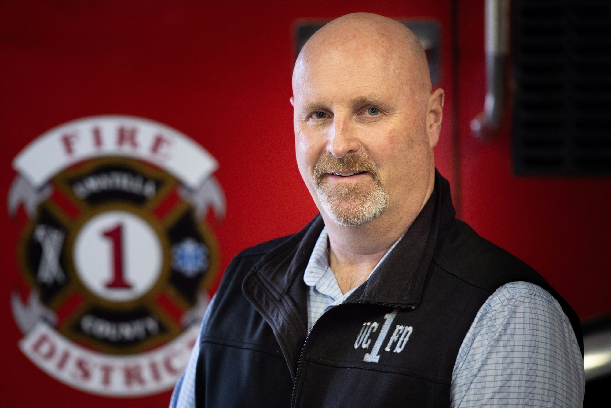 Contains a man named Scott Stanton sitting in front of a red fire engine.