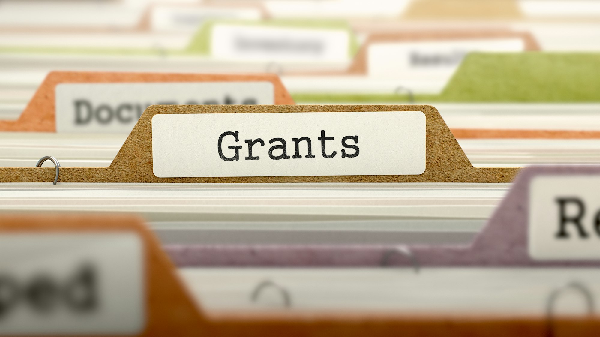 File folders with a tab marked "Grants" in a filing cabinet.