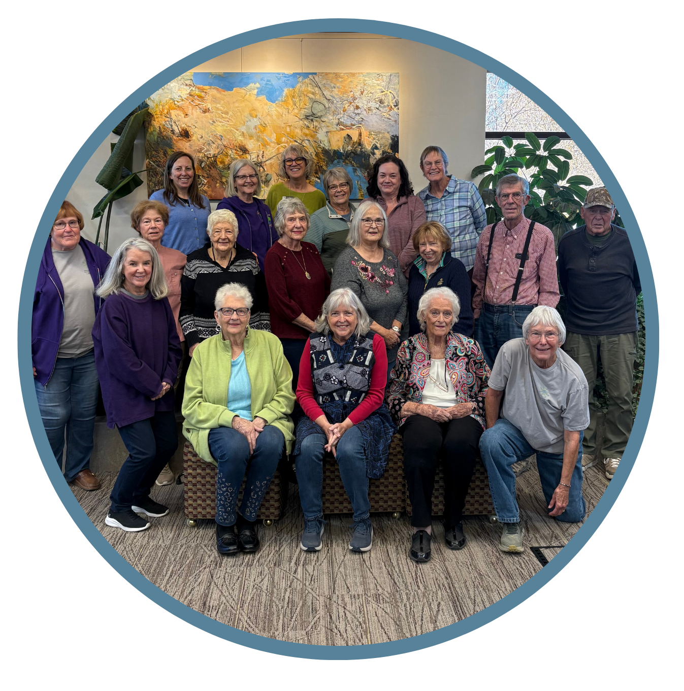 A diverse group of people posing for a photo in front of an abstract painting, smiling and gathered together.