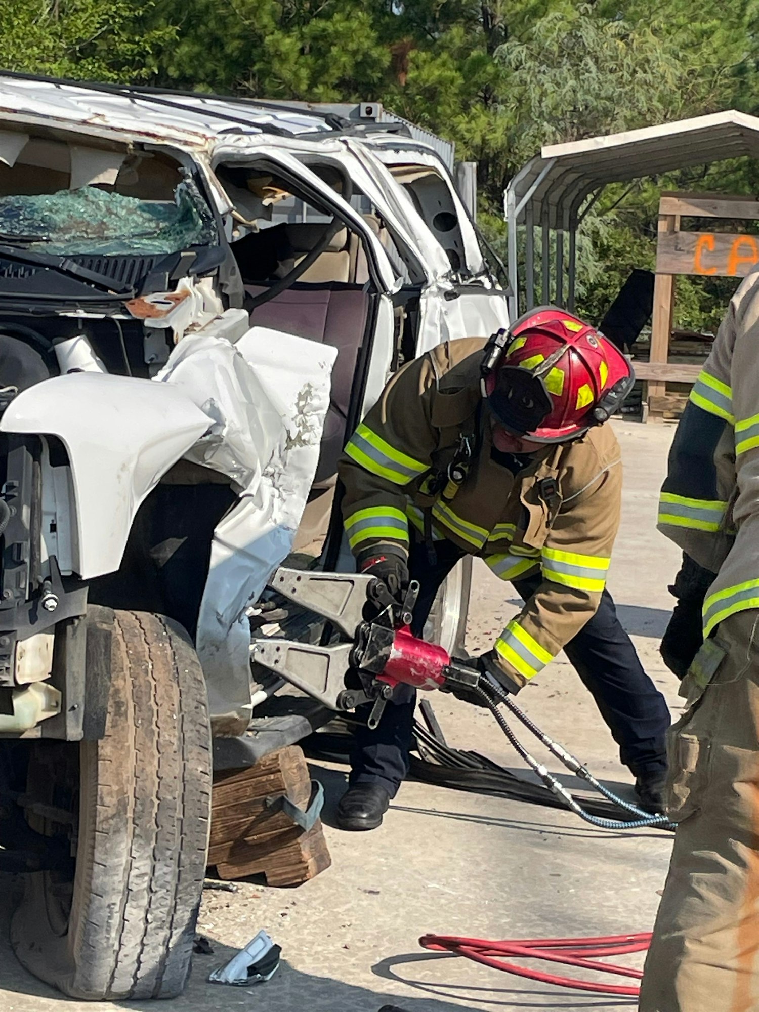 A firefighter is using hydraulic tools to extricate someone from a wrecked vehicle during a training exercise.