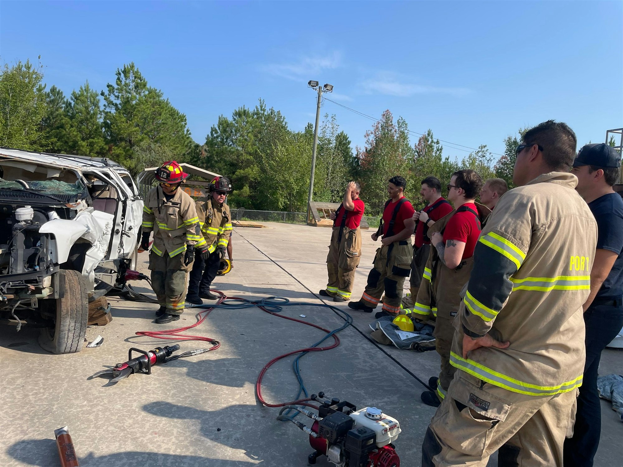 Firefighters are training with a wrecked vehicle, learning to use tools for emergency rescues.