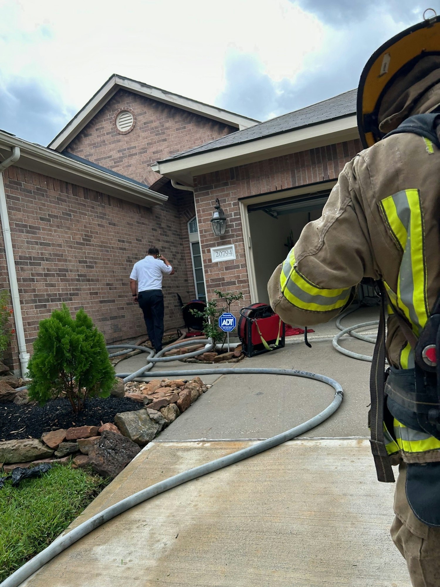 A firefighter approaches a residential entrance while another person stands by the door.