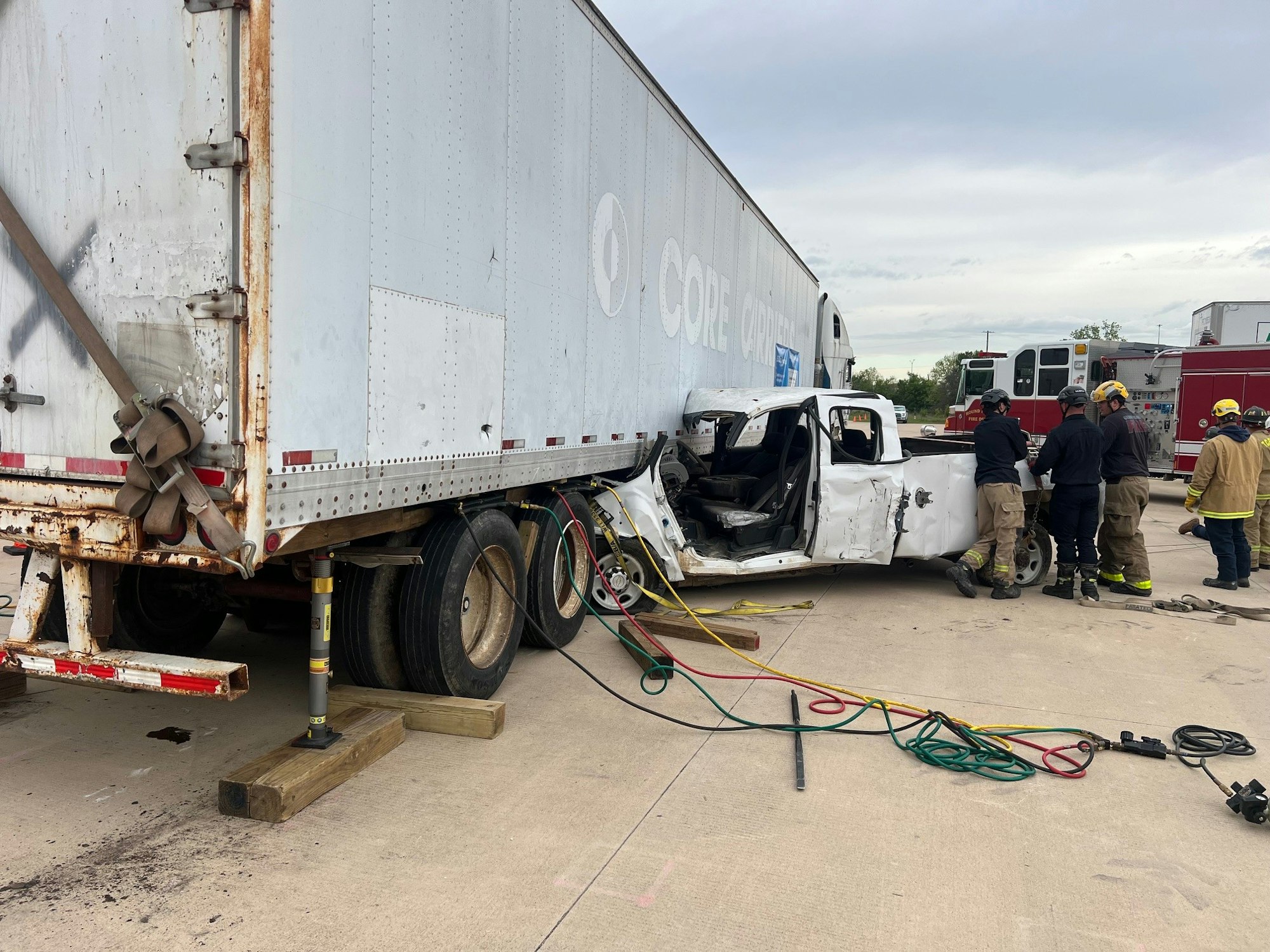 A vehicle collision involving a truck and a semi-trailer, with emergency responders on the scene.