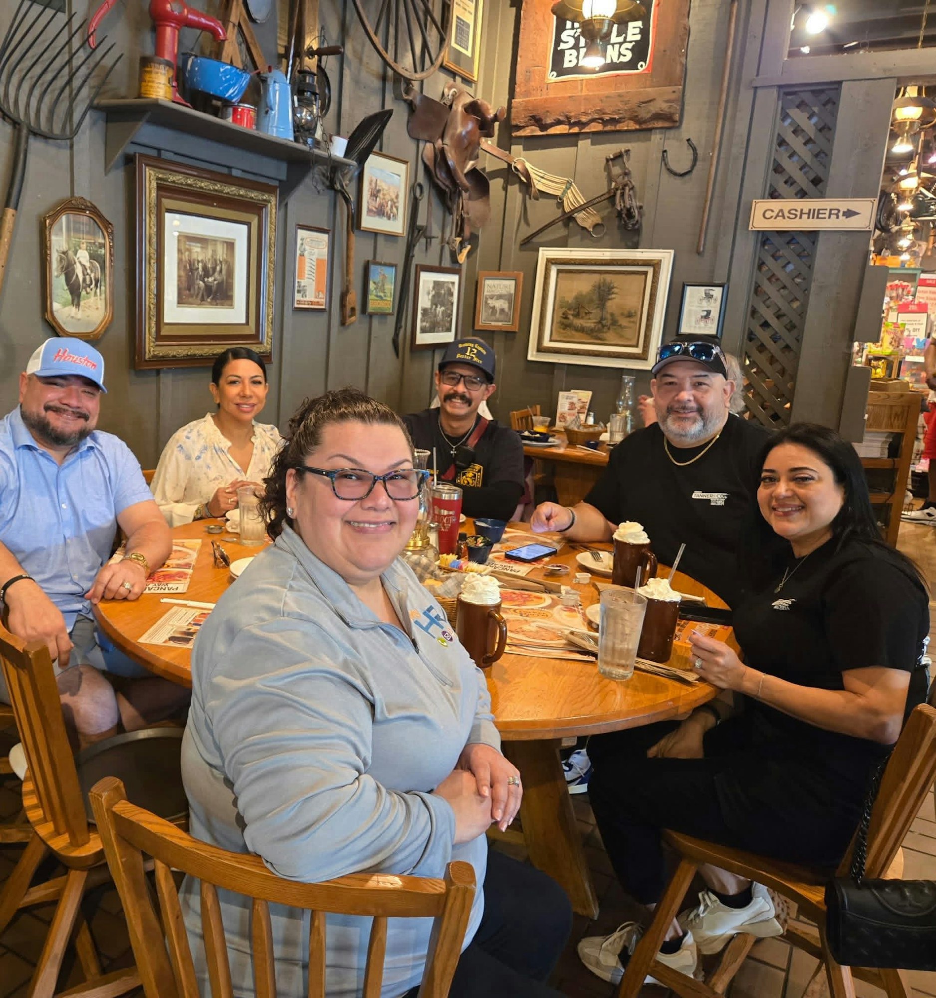 A group of six people is enjoying a meal together at a cozy restaurant, surrounded by rustic decor.
