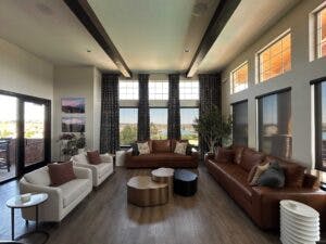 Modern living room with large windows, high ceiling, leather sofas, and a view outside.