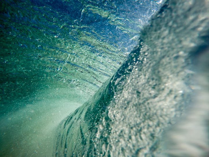 Underwater view capturing light refracting through water, displaying a blend of textures and bubbles.