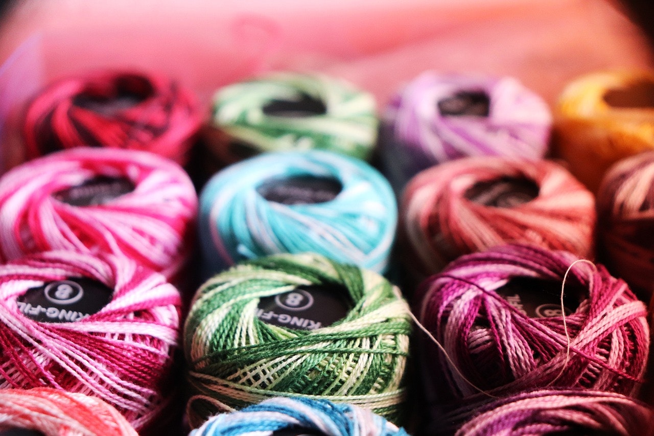 Colorful spools of thread arranged in rows, showcasing a variety of vibrant shades.