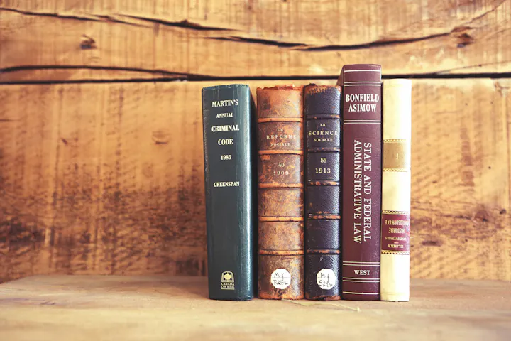 A collection of five books on law and social sciences, displayed on a wooden surface with a rustic background.
