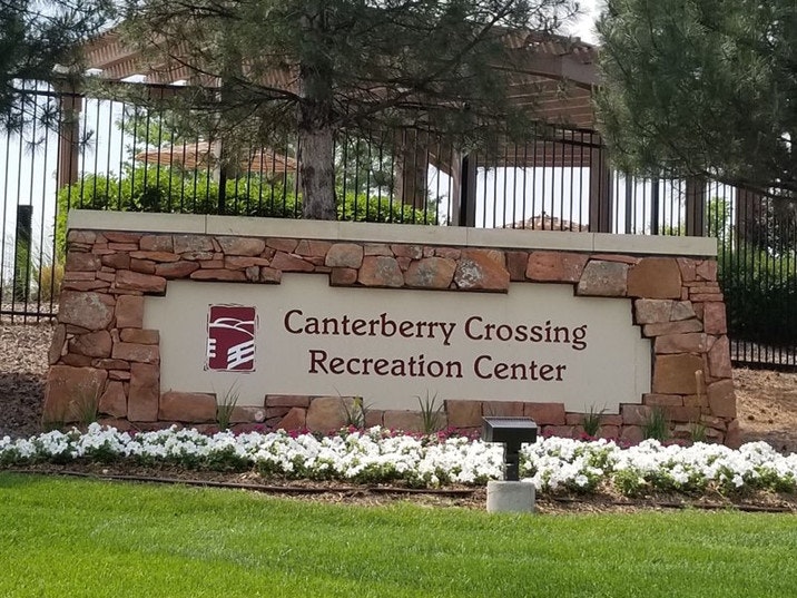Sign for "Canterberry Crossing Recreation Center" surrounded by flowers and trees.